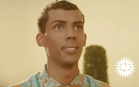 Ein Mann mit lockigem Haar und einem bunten Hemd blickt nach oben. Das Bild erinnert an die Bedeutung von "Papaoutai".