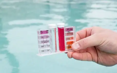 Testeur de piscine mesurant le chlore et le pH. La couleur rouge indique un niveau de chlore élevé, suggérant qu'il faut enlever le chlore de l'eau.