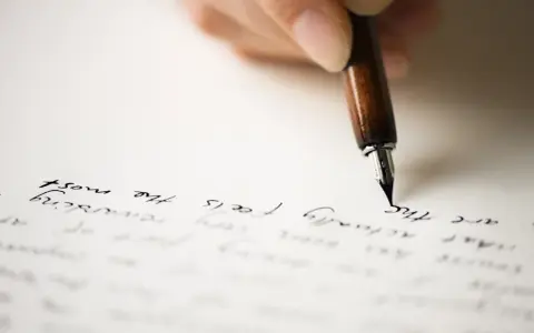 Mano che scrive con una penna stilografica su carta, evocando il significato di un rapporto epistolare.