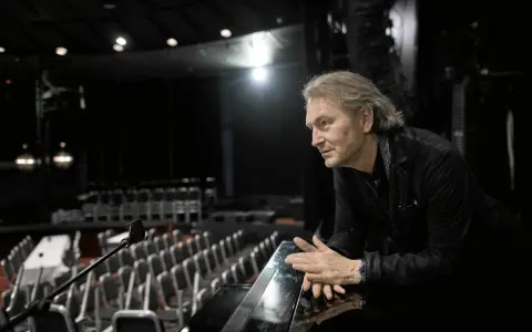 Tomas Ledin lutar sig mot en pianokant i en tom teatersalong, kanske förbereder han sig för Melodifestivalen.