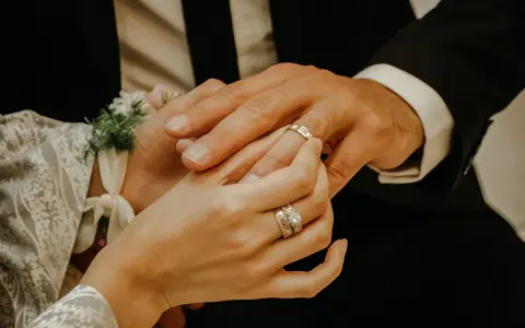 Dłoń panny młodej zakłada obrączkę na palec pana młodego. To ważny moment, jak pytania przed ślubem, symbolizujący miłość i przyszłość.