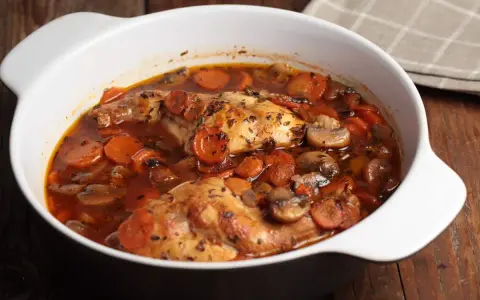 Conejo en cazuela con zanahorias y champiñones en salsa roja.
