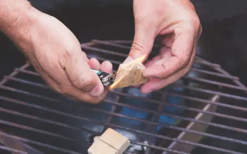 Hände zünden Grillanzünder an, um den Grill anzufeuern.