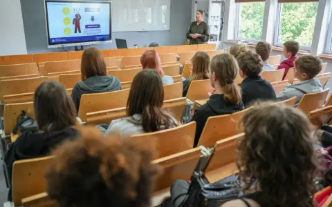 Wykład o przygotowaniu pedagogicznym dla psychologów. Studenci słuchają prelegentki przy tablicy interaktywnej.
