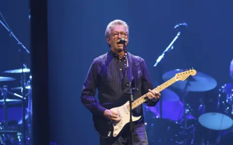 Eric Clapton gra na gitarze, wykonując swoje legendarne utwory.