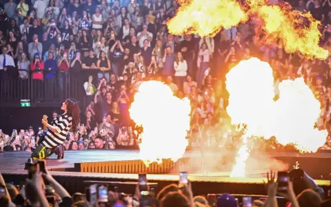 Billie Eilish ger en elektrisk Billie Eilish konsert med flammor som exploderar runt henne. Publiken filmar med sina mobiler.