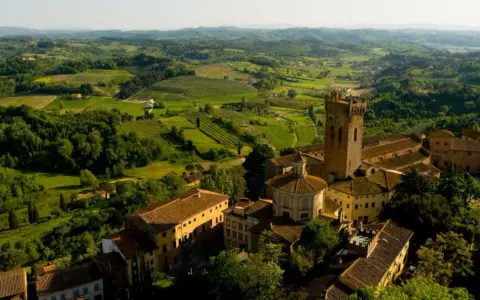 Un borgo medievale con una torre svetta tra le verdi colline pisane, un paesaggio da cartolina.