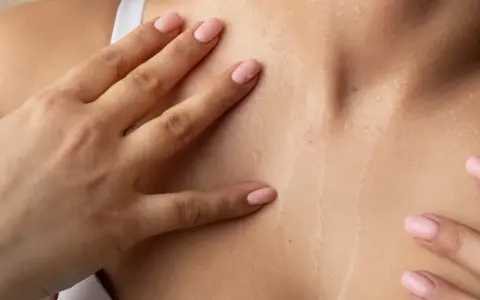 Mani accarezzano la pelle naturale cos'è: idratata e luminosa, con goccioline d'acqua che riflettono la luce.