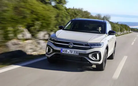 Jasnoszary Volkswagen T-Roc jedzie po krętej drodze. Nawet przy potencjalnych usterkach, ten model prezentuje się dynamicznie.