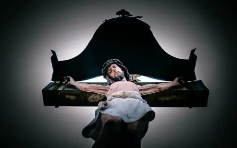A statue of Jesus on the cross, with a dark canopy above. This image evokes the sacrifice and the question of why Jesus died.