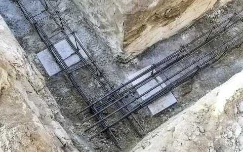 Zbrojenie płyty fundamentowej w wykopie. Stalowe pręty tworzą siatkę, gotową na zalanie betonem.