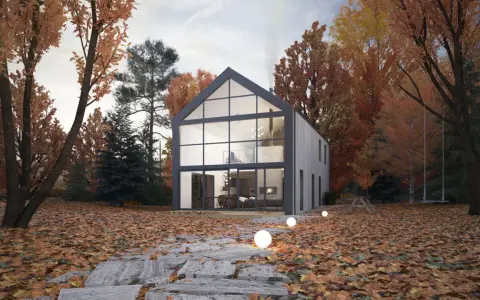 Maison moderne avec un grand pignon vitré, entourée d'arbres aux couleurs d'automne. Un chemin de dalles mène à la porte d'entrée.