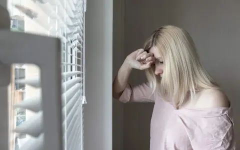 Mujer rubia con la mano en la frente, mirando hacia abajo, con un aire de melancolía que evoca el síndrome de Wendy.