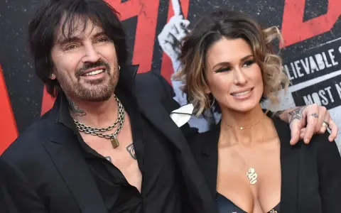 Tommy Lee i jego żona, Brittany Furlan, uśmiechają się do aparatu na czerwonym dywanie.