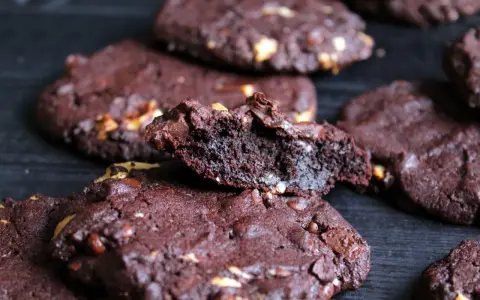 Schokoladenkekse mit Nüssen, die an das subway cookies rezept erinnern. Ein Keks ist zerbrochen und zeigt die saftige Innenseite.