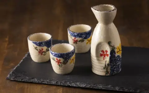 Zestaw do sake z ceramicznym dzbankiem i trzema kieliszkami, ozdobiony motywem kwiatowym. Idealny do degustacji sake, niezależnie od tego, sake ile procent ma zawartości alkoholu.