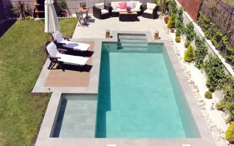 Un jardín con piscinas modernas, tumbonas, zona de estar y barbacoa.
