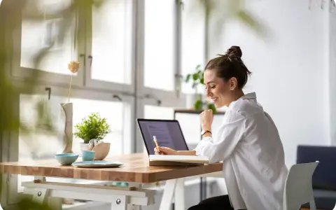 Uśmiechnięta kobieta pracuje przy laptopie, planując swój **ecommerce dropshipping**. Sukces w biznesie online!