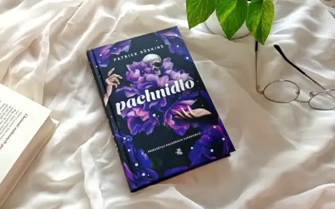 Powieść Patricka Süskinda "Pachnidło" na tle białej tkaniny, obok okularów i innej książki.