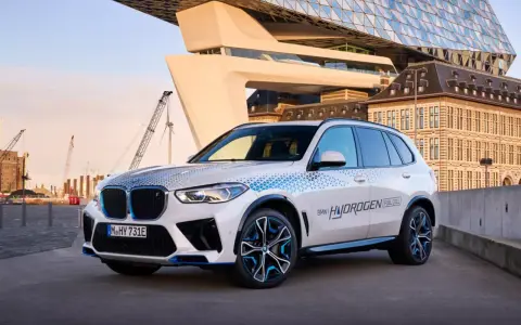 BMW iX5 Hydrogen, ein Vorreiter unter den BMW Elektro Modellen, mit futuristischer Architektur im Hintergrund.