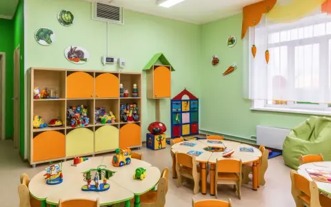 Kolorowa sala przedszkolna z zabawkami i stolikami. Zastanawiasz się, ile kosztuje żłobek? To miejsce wygląda na przyjazne dla dzieci.