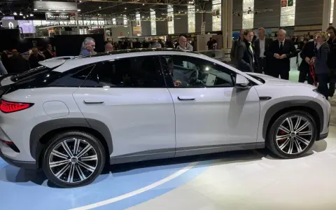 En vit BYD-bil visas på en mässa. Människor tittar på bilen, kanske potentiella byd återförsäljare.