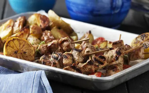 Grillade souvlaki-spett med rostade potatisar och citronklyftor. Ett perfekt souvlaki recept för en härlig middag.