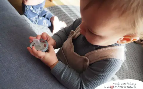 Dziecko trzyma smoczek, zastanawiając się, jak odzwyczaić dziecko od smoczka. Czas na zmiany!