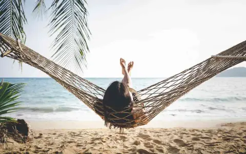 Relaks na plaży w hamaku, idealny opis wakacji po angielsku. Słońce, morze i palmy tworzą rajski widok.