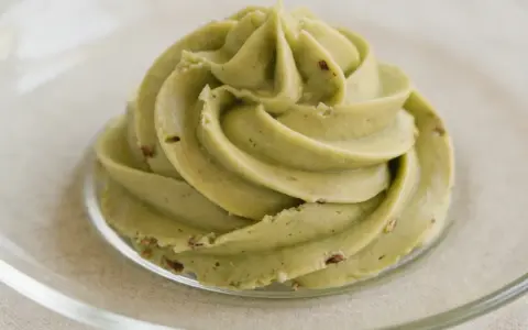 Puszysty krem pistacjowy do tortu, udekorowany na talerzyku.