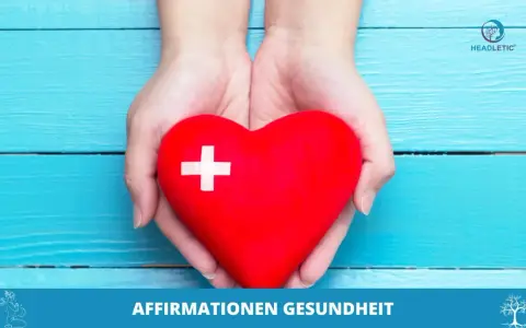 Hände halten ein rotes Herz mit einem weißen Kreuz. Es symbolisiert positive Affirmationen für Gesundheit und Wohlbefinden.