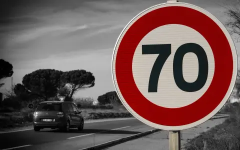 Segnale 226: limite di velocità 70. Un'auto viaggia su una strada panoramica.