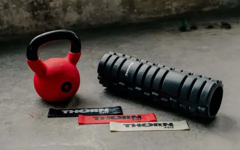 Czerwony kettlebell, wałek do masażu i taśmy oporowe. Idealny zestaw, by zacząć treningi z kettlebell.