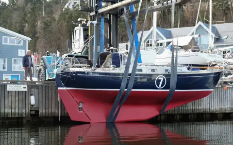 Ein Mann beobachtet, wie ein Rustler 36 namens "Olleanna" mit einem Kran aus dem Wasser gehoben wird.