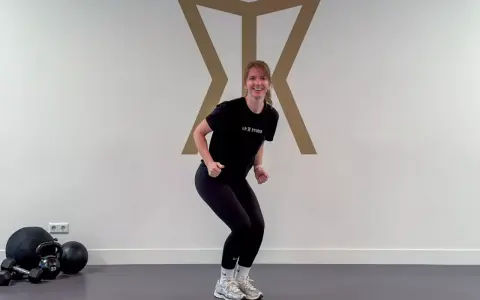 Frau in Sportkleidung macht eine Kniebeuge, bereit für das Skifahren. Krafttraining für die Pisten.
