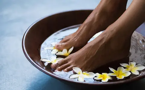 Relaxing foot bath with frangipani flowers. The amount of epsom salt in a foot bath can vary, but a common recommendation is 1/2 cup per gallon of water for a soothing soak.