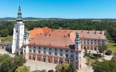 Imponujący Henryków zamek z wieżami i czerwonymi dachami, otoczony zielenią.