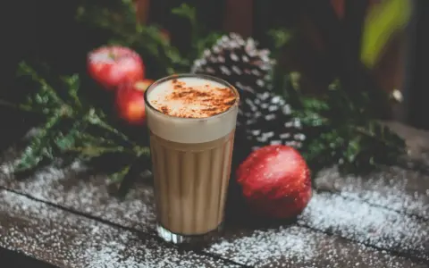 En krämig kaffedrink med kanel, omgiven av juliga äpplen och granris. Perfekt för mysiga stunder och inspirerar till egna kaffedrinkar recept.