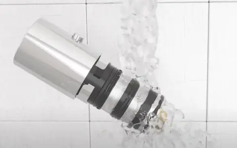 Detalle de un grifo termostático bajo un chorro de agua, mostrando su diseño y cómo limpiarlo.