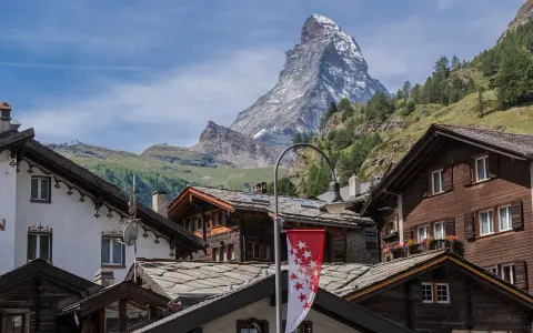 Tradycyjna winieta szwajcaria: drewniane domy z kamiennymi dachami i majestatyczny Matterhorn w tle.