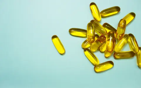 En hög med genomskinliga, gulaktiga kapslar som innehåller alla vitaminer.