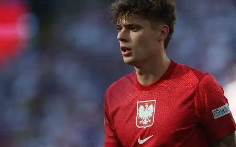 Młody piłkarz w czerwonej koszulce z orłem, symbolizujący polską reprezentację. Jego wzrost i determinacja na boisku budzą nadzieję na przyszłe sukcesy.