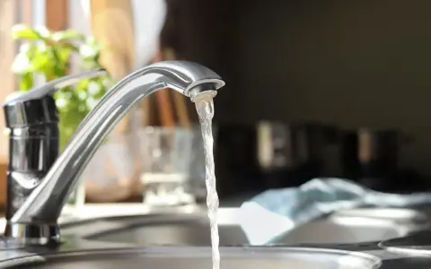 Wasserhahn mit integriertem Durchlauferhitzer, Testsieger. Wasser fließt aus dem Hahn in die Spüle.