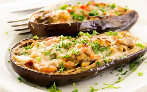 Berenjenas rellenas de carne picada, gratinadas con queso y perejil fresco. Un plato casero y delicioso.