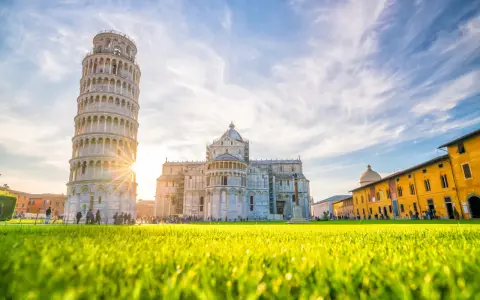 Torre di Pisa e Duomo, tra i più bei posti da visitare in Toscana, con un prato verde brillante e cielo azzurro.