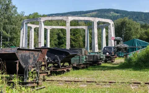 Ruiny budowli w muzeum molke, obok stare wagony kopalniane, ciężarówka i zielony namiot.