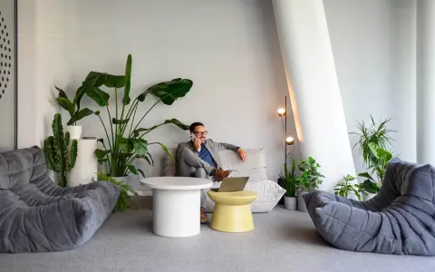 Un homme d'affaires au téléphone dans un coin salon moderne avec des plantes, une idée pour optimiser petit espace.