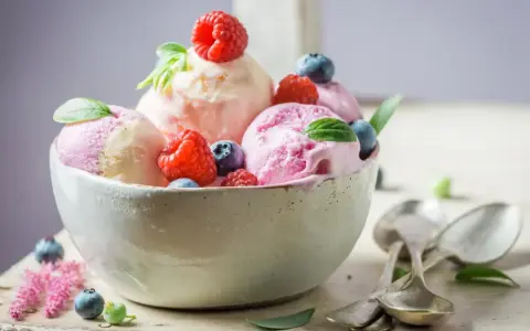 Deliciosos helados caseros de fresa y vainilla, adornados con frambuesas y arándanos frescos.