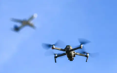 Drohne im Flug, während ein Flugzeug im Hintergrund verschwimmt. Informiere dich über Länder, in welchen Ländern Drohnen verboten sind, bevor du abhebst.
