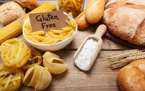 Miesiąc bez glutenu efekty: makarony, pieczywo i mąka na drewnianym stole.